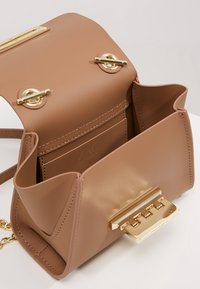 Borsa a tracolla in pelle color cuoio con chiusura e accessori in tonalità oro. Presenta una tasca interna e una texture liscia, con un design strutturato.