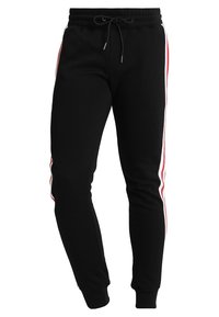 Zwarte joggingsbroeken met een elastische tailleband, trekkoord, aangesloten enkels en witte en rode strepen die langs de buitenkanten van beide benen lopen.