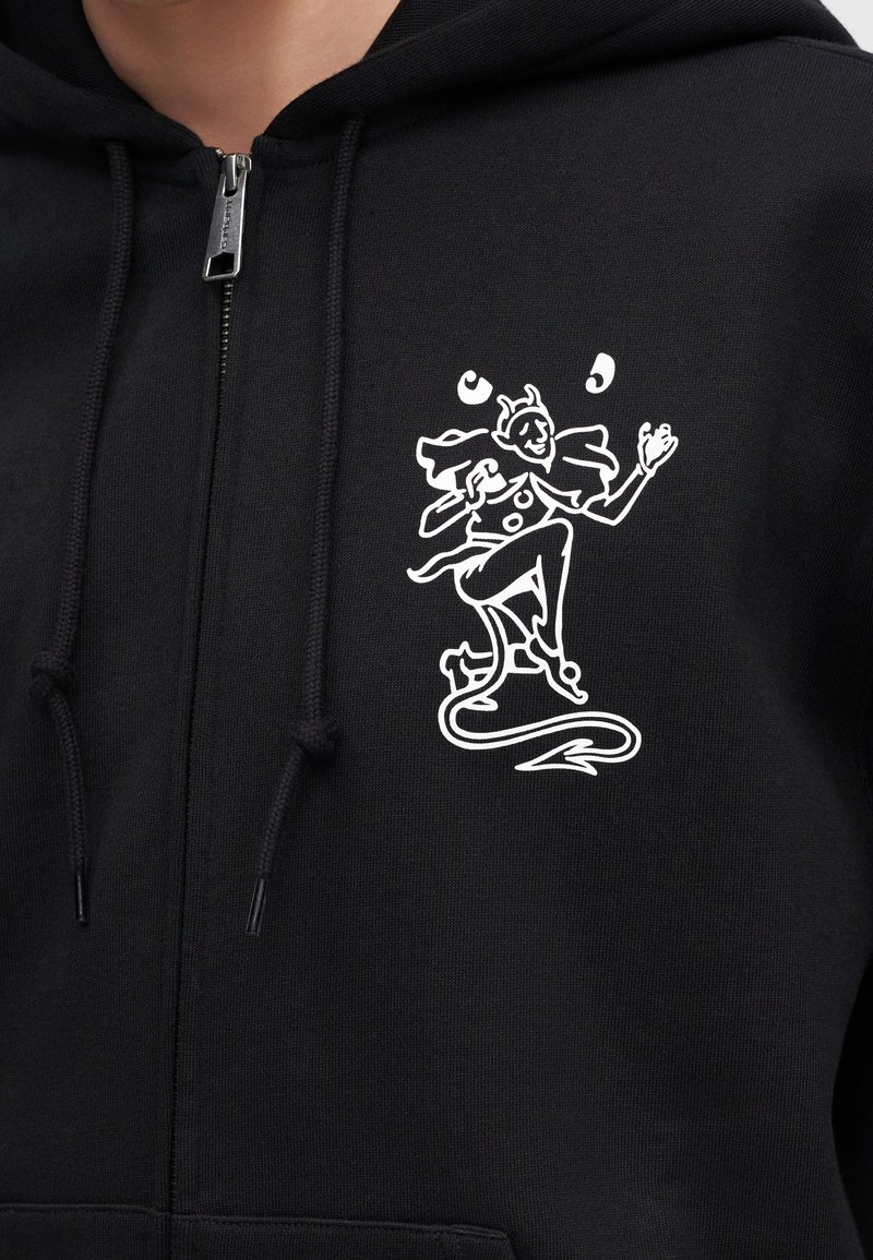Schwarzer Hoodie mit weißer Linienzeichnung eines tanzenden Narren, der auf der linken Brust drei Bälle jongliert.