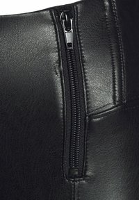 Giacca di pelle nera con zip verticale sul lato sinistro, dalla texture liscia e con cuciture dettagliate lungo la cucitura.