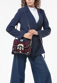 Borsa multicolore con ricami floreali, dotata di una tracolla nera, dettagli in catena dorata e forma rettangolare.