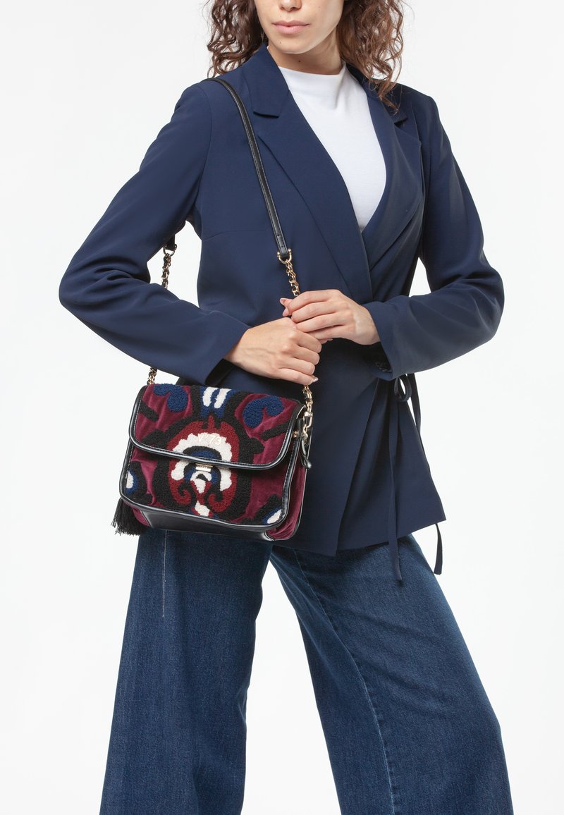 Borsa multicolore con ricami floreali, dotata di una tracolla nera, dettagli in catena dorata e forma rettangolare.