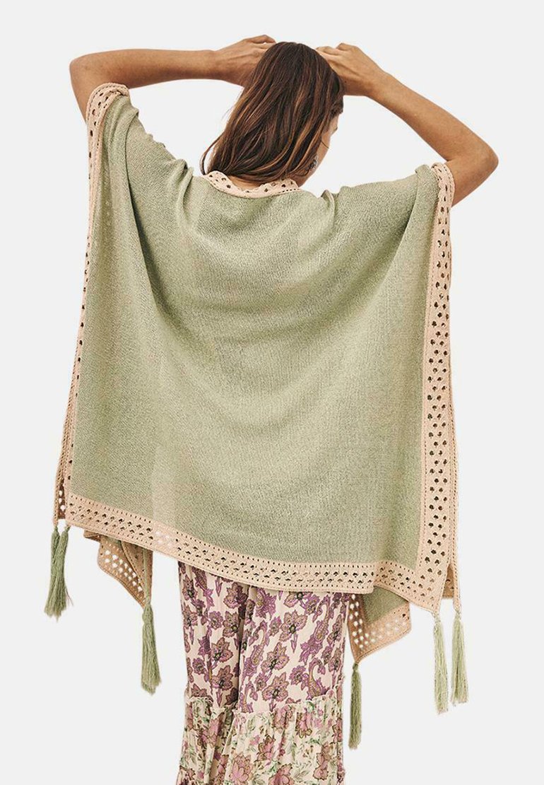 Poncho verde claro de corte holgado, decorado con un ribete de encaje crema y borlas en las esquinas, con una textura de punto suave.