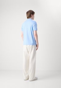 Világoskék, rövid ujjú, slim fit pólóing, laza fehér nadrággal párosítva. Kényelmes pamut keverék, minimális dizájn, minta nélkül.