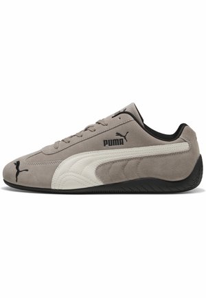 Szary zamszowy sneaker Puma z białym skórzanym paskiem po boku, czarna podeszwa, czarne logo Puma z boku, na języku i na nosku, nisko wycięty fason.