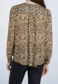 Langärmlige, durchsichtige Bluse in Beige mit einem schwarzen Tigerstreifenmuster, mit einem runden Ausschnitt und rüschendetail am Rücken.