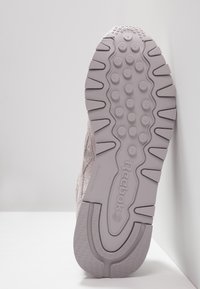 Reebok sneakersula i ljuslavendel med texturerat gummi, cirkulära grepp och uttalade mönster. Har logotypen präglad på ytterkanten.