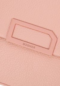 Pink lædertaske med en struktureret overflade, et rektangulært hardware-element og mærkenavnet "BOGNER" præget foran.