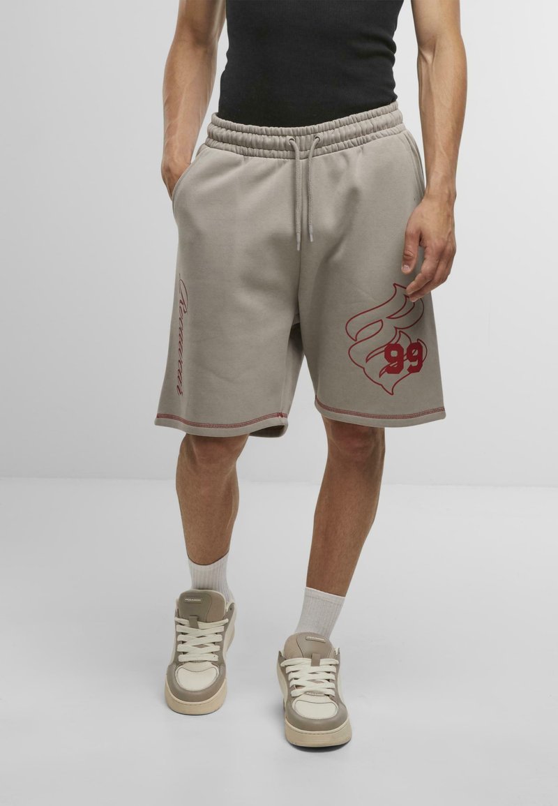 Lys grå bomuldsblandingsshorts med broderede røde grafik, elastisk talje og sidelommer. Stylings med beige højhælede sneakers.