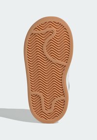 Suela de goma con un patrón ondulado en marrón claro. El diseño presenta surcos y contornos texturizados para proporcionar tracción y agarre.