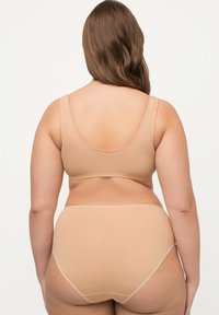 Conjunto de lencería nude con una tela suave y elástica. El sujetador tiene tirantes anchos y un respaldo redondeado, mientras que las bragas de cintura alta son del mismo color.
