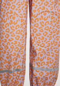 Dažďové nohavice s leopardím vzorom v svetlofialovej farbe s oranžovými škvrnami, reflexné akcenty a polstrovanie na kolenách pre zvýšenú ochranu.