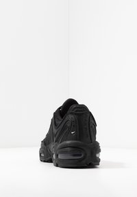 Černá sportovní obuv s texturovaným svrchním materiálem, zakřiveným designem a viditelným vzduchovým polstrováním. Doplňky zahrnují malé logo a detail „MAX AIR“.