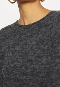 Maglione grigio lavorato a maglia con scollatura rotonda, morbido al tatto e con un motivo sottile. La vista ravvicinata mette in evidenza la profondità e il calore del tessuto.