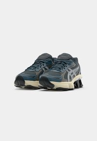 Baskets de sport bleues avec des accents gris, tige en mesh texturé, col rembourré et semelle extérieure en caoutchouc noir avec un design segmenté distinct.