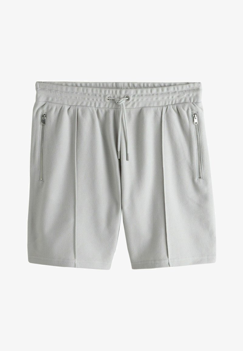 Shorts de sport gris clair texturés avec une ceinture élastique, un cordon de serrage et des poches zippées verticales de chaque côté.