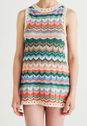 Mouwloze gebreide jurk met meerkleurige chevronstrepen in oranje, groen, blauw en crème, afgewerkt met een geschulpte crèmekleurige rand bij de halslijn en zoom.