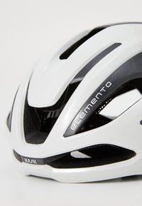 Weißer Fahrradhelm, schräg angeordnet, um Belüftungsöffnungen und Logos zu zeigen. Verfügt über ein glattes Design und schwarze Akzente, geeignet für die Sicherheit beim Radfahren.