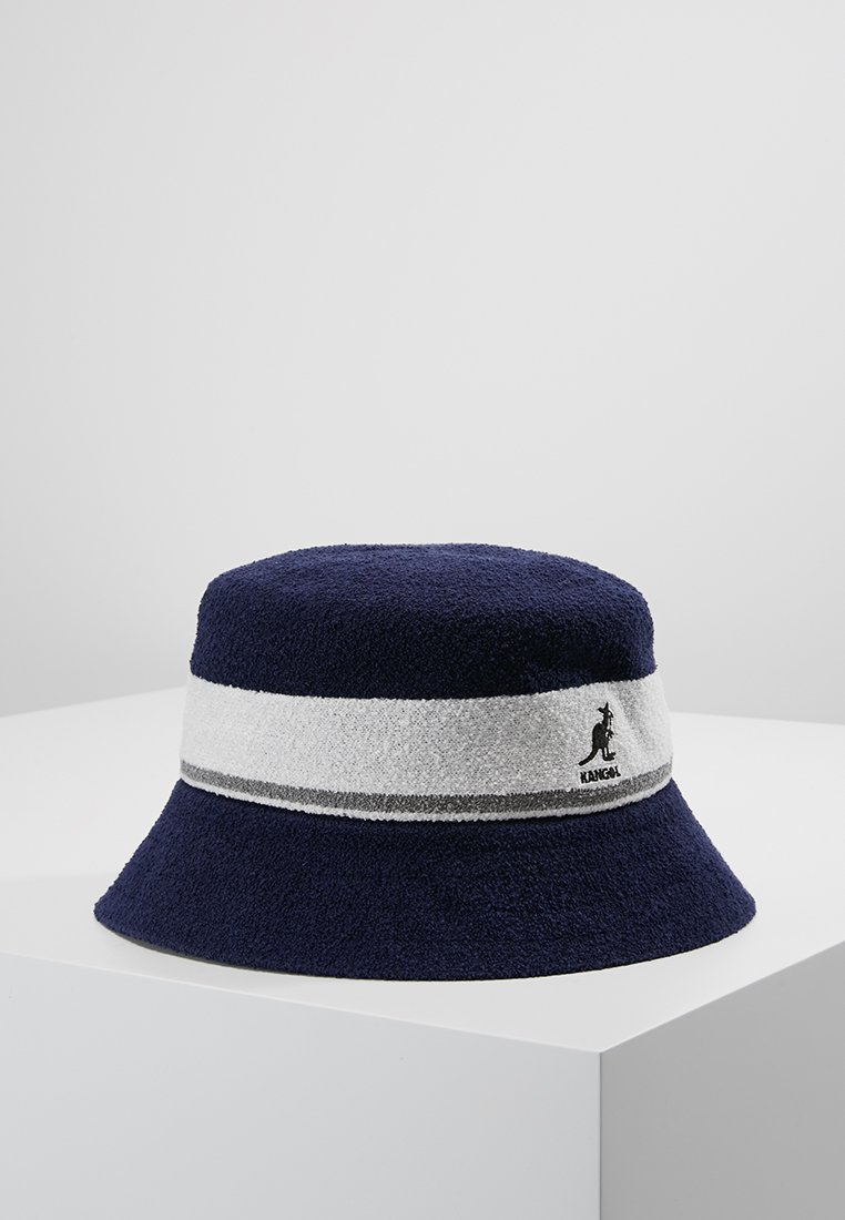Chapeau seau bleu marine en matériau texturé, avec une bande blanche à rayures grises et un logo noir à l'avant.