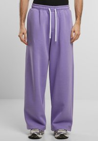 Fioletowe dresy o luźnym kroju, z elastycznym pasem i białym sznurkiem. Miękka tekstura materiału z bocznymi kieszeniami.