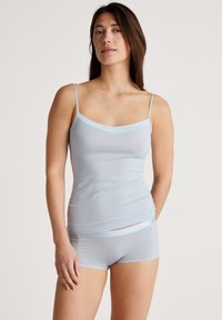 Lichtblauwe cami met dunne spaghettibandjes en een V-hals, gecombineerd met bijpassende boyshorts. Beide gemaakt van een glad, rekbaar materiaal.