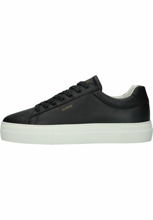Sneaker in pelle nera con suola piatta bianca. Le caratteristiche includono lacci tondi, una texture liscia e un branding minimale in oro.