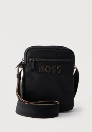 Čierna crossbody taška s predným vreckom na zips, širokým popruhom s hnedými lemami a logom „BOSS“ v čiernych a hnedých písmenách.
