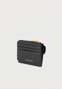 Musta nahkainen korttikotelo, jossa vetoketjullinen lokero, neljä korttitaskua ja kullanvärinen logoyksityiskohta edessä. Tasainen pinta.