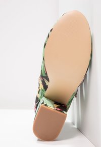 Buty w kwiatowy wzór z czarną bazą, w odcieniach zieleni, żółci i różu. Gładka gumowa podeszwa z teksturowanym gripem. Kwadratowy obcas.