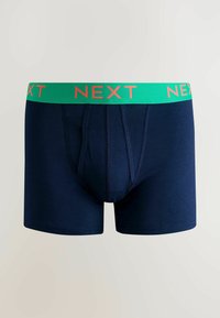 Námořnické bavlněné boxerky se zeleným elastickým pasem, na kterém je nápis "NEXT" v oranžové barvě. Mají přední kapsu a švy jako detaily.