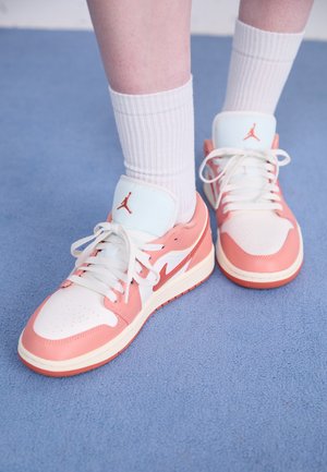 Pink and white leather sneakers with a smooth texture, featuring white laces and an embroidered logo on the tongue. Rubber sole.