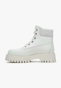 Witte leren enkellaarsjes met een suède kraag, ronde neus en dikke, geserreerde witte rubberen zool. Voorzien van zilveren oogjes en veters.