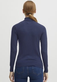 Marinblå stickad tröja med långa ärmar och ribbad nederkant, med en slät textur och slimmad passform.