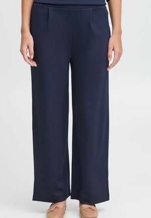 Pantaloni largi de culoare bleumarin, dintr-un material neted, cu pliuri în față și un tiv curat. Asortați cu pantofi joși de culoare deschisă.