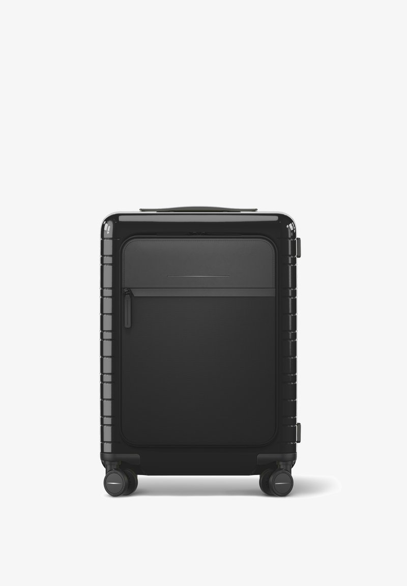 Valise rigide noire avec une texture lisse, poche zippée à l'avant, accents horizontaux et quatre roulettes pivotantes pour la mobilité.