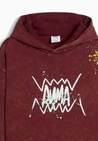 Vinröd hoodie med en framsida som har texten "AUMA" i vitt, tillsammans med gröna och gula färgfläckar. Mjuk textur, avslappnad design.