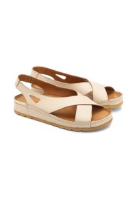 Jasnobeżowe skórzane sandały z krzyżującymi się paskami, odkrytą piętą i wycięciami. Posiadają wyściełane taniną wkładki oraz gumową podeszwę.
