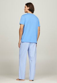 Maglietta in cotone azzurro chiaro con maniche corte, abbinata a pantaloni da pigiama azzurro chiaro a righe, caratterizzati da una vestibilità comoda e gambe dritte.