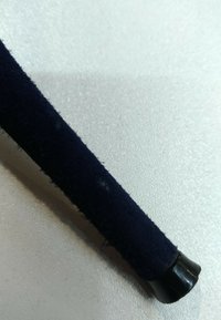 Gros plan d’une poignée recouverte d’un tissu bleu foncé avec une embout en plastique noir reposant sur une surface blanche texturée.