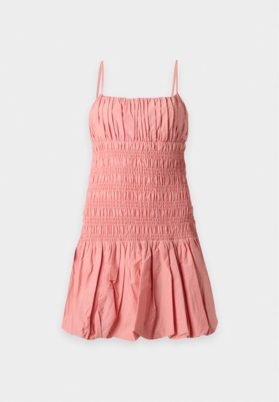 Robe courte rose sans manches avec fines bretelles, corsage smocké et jupe froncée sur un fond clair uni.