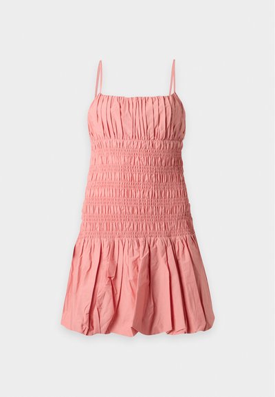 Robe courte rose sans manches avec fines bretelles, corsage smocké et jupe froncée sur un fond clair uni.