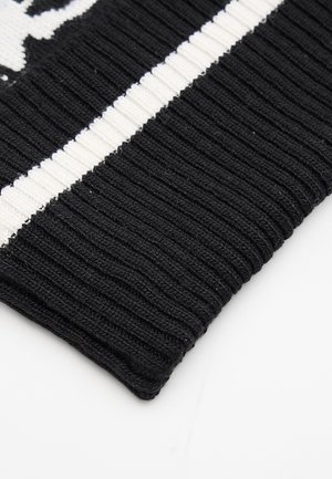 Tela de punto acanalado en blanco y negro con una franja blanca gruesa en el centro sobre un fondo negro.