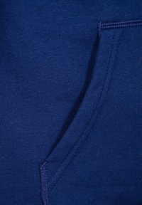 Tessuto blu navy, con una texture morbida, caratterizzato da una tasca frontale con cuciture visibili. Il materiale appare resistente e liscio.