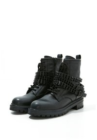 Svarta läderankelstövlar med en texturerad yta, med blixtlås stängning, snörningsdesign och nitar för extra detalj. Platta gummisålar.