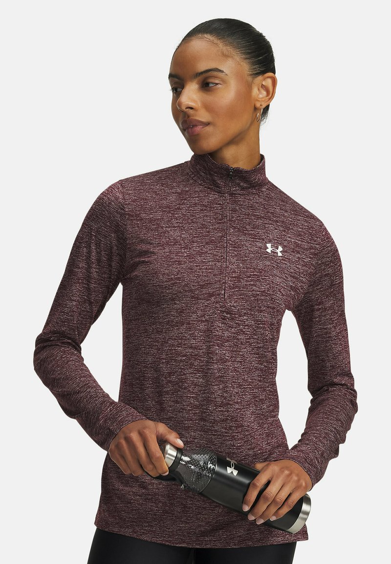 Maroon long-sleeve zip-up top with a high collar, textured fabric, and reflective logo, paired with a black insulated water bottle.