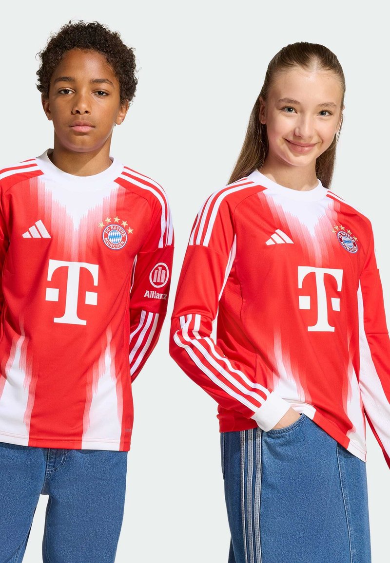 Rode voetbalshirts met lange mouwen, met witte accenten, teamlogo en branding. Het ontwerp bevat een gradiëntverloop en drie strepen op de mouwen.