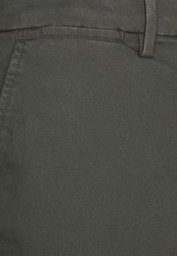 Pantalon gris foncé en denim, caractérisé par une texture lisse, une coupe slim, des poches avant standard avec passants pour ceinture et des détails de coutures.