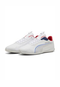 Hvide sneakers med en glat overdel, røde og blå detaljer, perforerede elementer på siden og flade gummisåler. Snørebånd til fastgørelse.