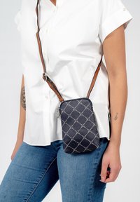 Borsa a tracolla blu navy con motivo trapuntato, cinturino marrone, dettagli in argento e chiusura con zip. La texture del tessuto è liscia e resistente.