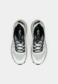 Sport Schuhe mit einem leichten Mesh-Obermaterial in Weiß und Grau, ausgestattet mit schwarzen Schnürsenkeln, dezentem Branding und einer gepolsterten Sohle für Komfort.